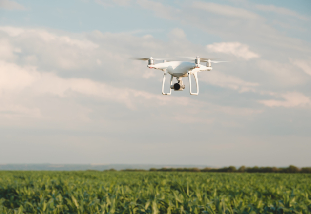 White drone hovering in a bright blue sky. Drone copter flying with digital camera